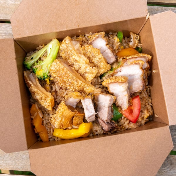 Crispy pork belly with fried rice, broccoli, and peppers in a brown takeout container.